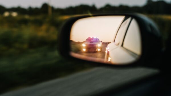 car mirror reflection showing police car with lights on
